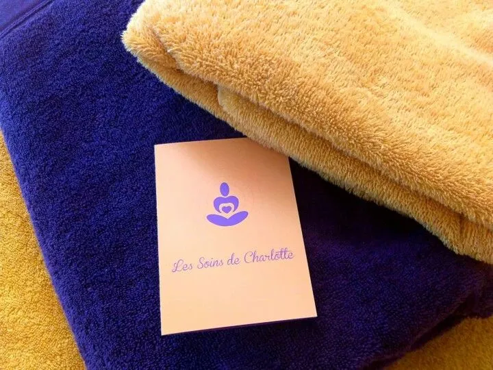 Serviettes moelleuses et carte de l'institut Les Soins de Charlotte, préparées pour un soin à Genval